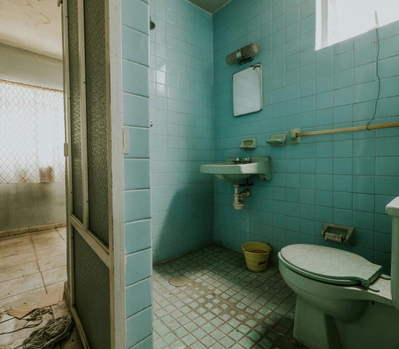 pexels-photo-18644893-18644893 An abandoned bathroom with blue tiles, old fixtures, and a worn-out look.