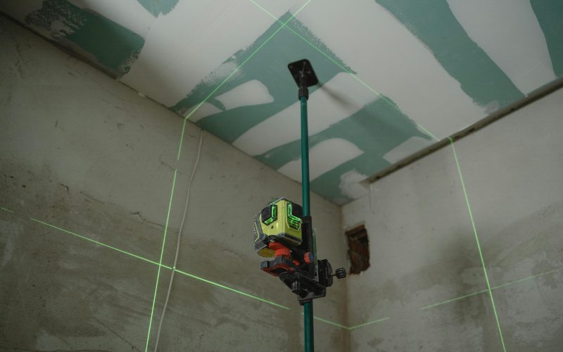 A laser level tool in action at an indoor construction site with marked walls.